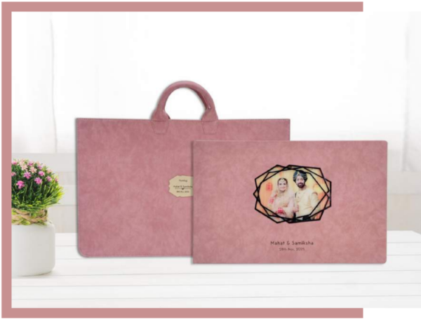 Luxury custom photo album with a blush fabric cover and geometric picture window, shown with a matching premium carrying bag.